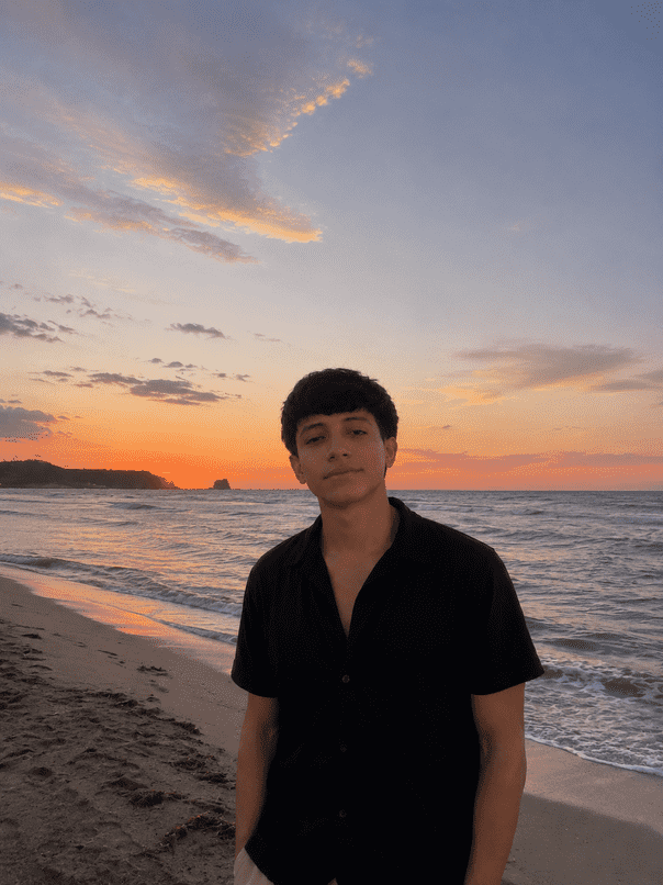 Noah Dylan standing on a beach at sunset